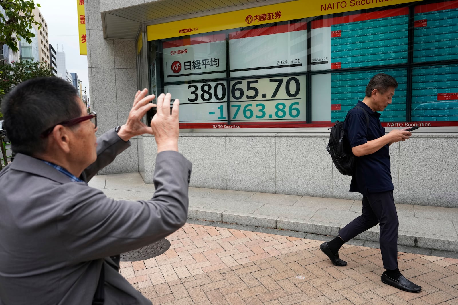 A man who called himself a trader takes a picture of monitors showing Japan's Nikkei 225 index at a securities firm in Tokyo, Monday, Sept. 30, 2024. (AP Photo/Hiro Komae)