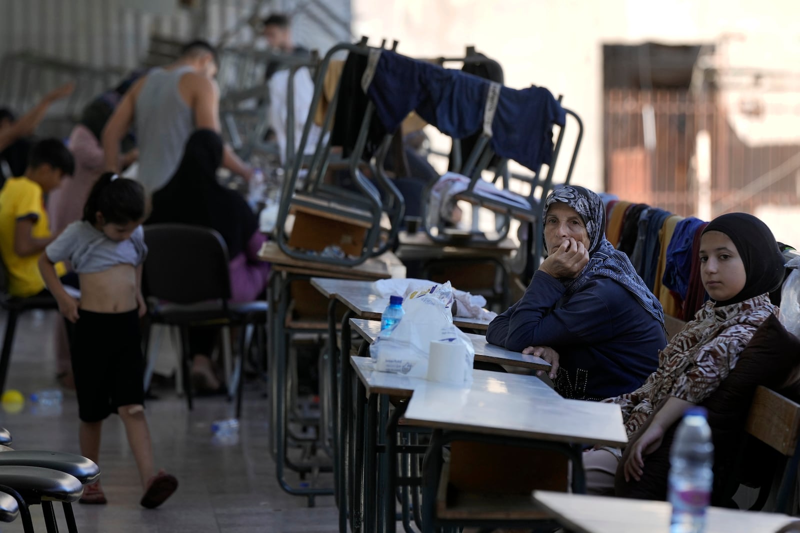 Displaced women and children sit in a classroom in Beirut, after fleeing the Israeli airstrikes in the south, Thursday, Sept. 26, 2024. (AP Photo/Bilal Hussein)