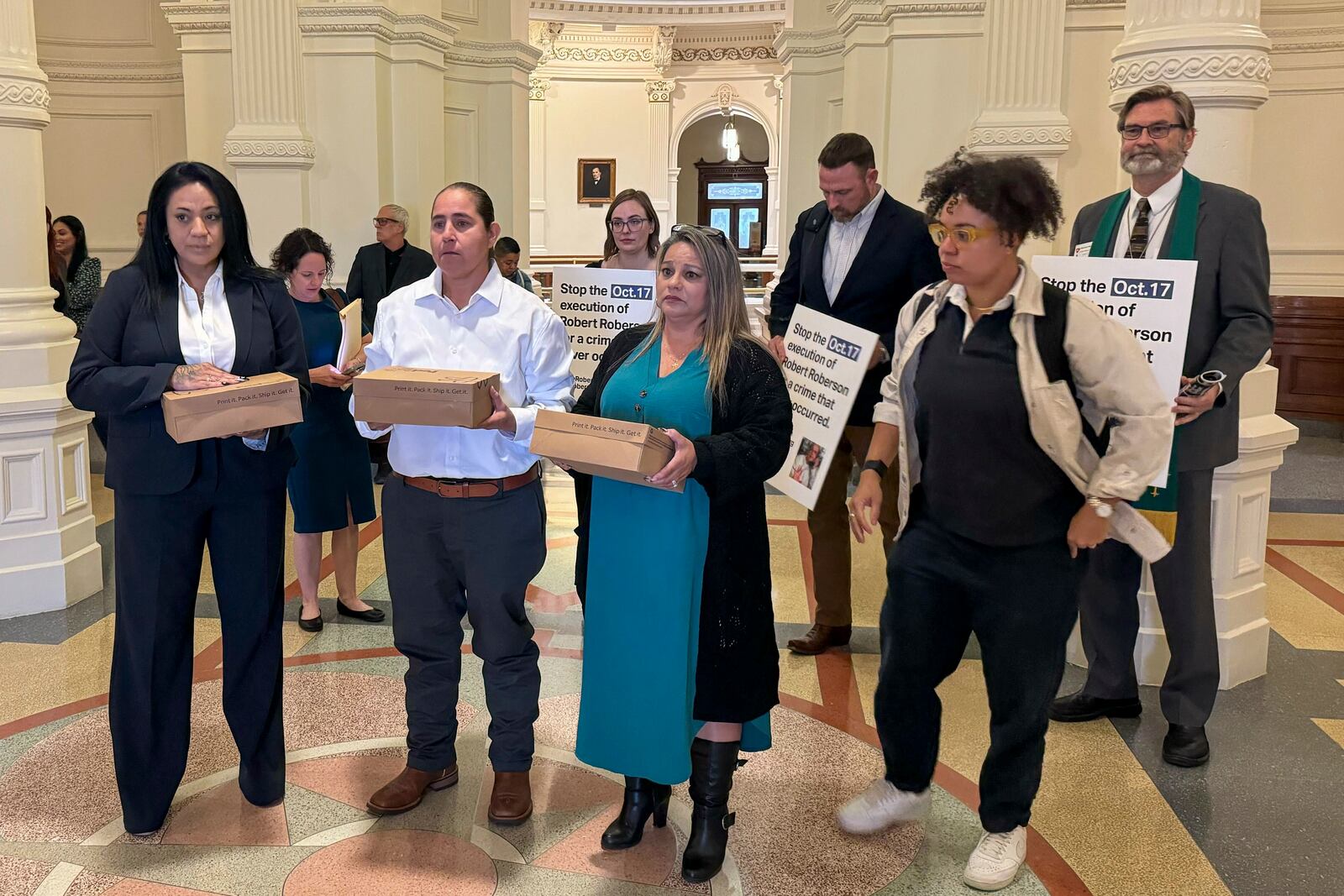 Casandra Rivera, left, Anna Vasquez, second from left, and Elizabeth Ramirez, center, of the "San Antonio 4" group, hold boxes with petitions being delivered in the Texas State capitol for Texas Gov. Greg Abbott seeking the pardoning of Robert Roberson's execution, Wednesday, Oct. 16, 2024 in Austin, Texas. Roberson, 57, is scheduled to receive a lethal injection on Oct. 17, for the 2002 killing of his 2-year-old daughter, Nikki Curtis, in the East Texas city of Palestine. Roberson has long proclaimed his innocence. (AP Photo/Nadia Lathan)