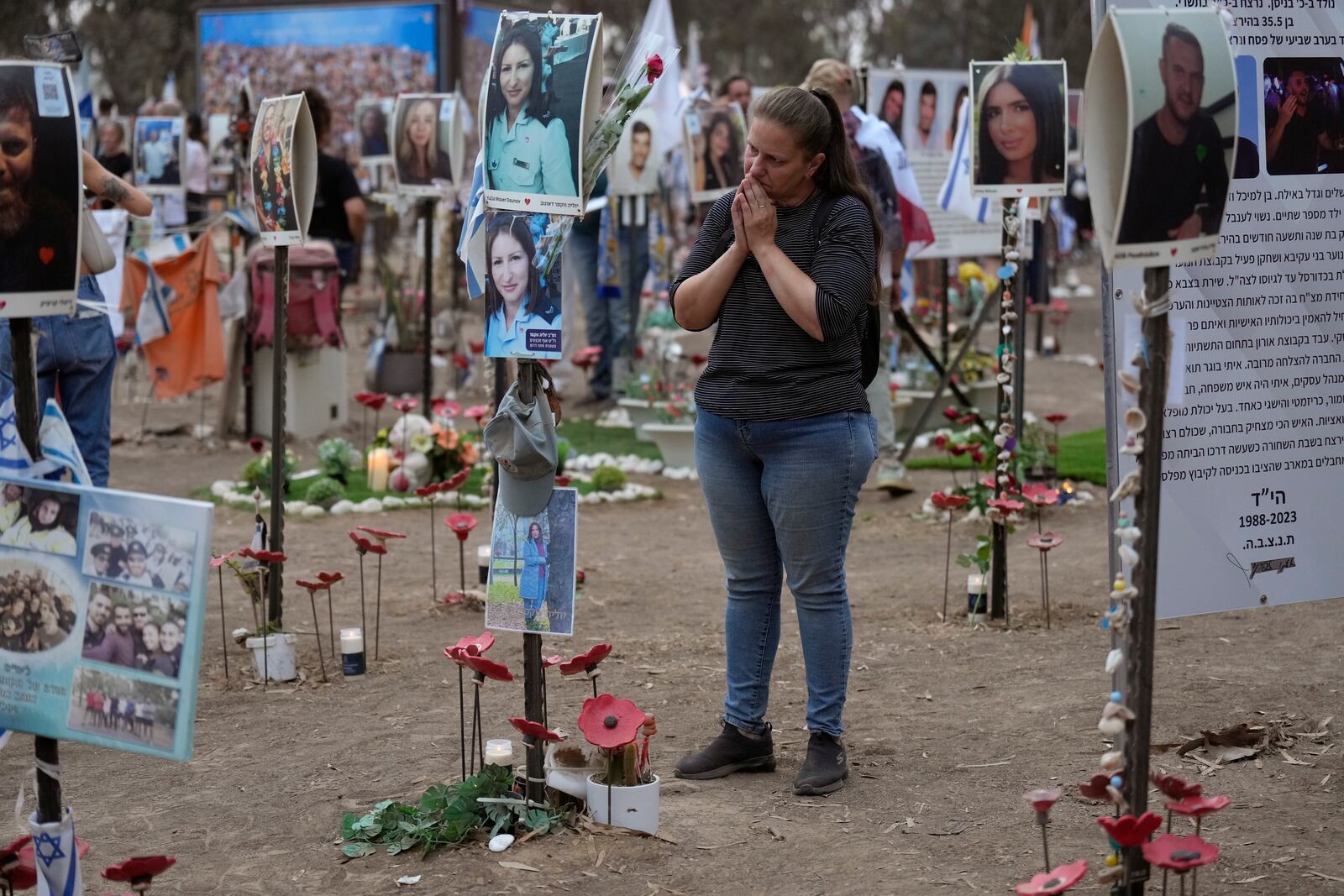 Victoria stands in front a picture of her sister, Yulia Waxer Daunt, as she visits the site of the Nova music festival, where hundreds of revelers were killed and abducted by Hamas and taken into Gaza, on the one-year anniversary of the attack, near Kibbutz Reim, southern Israel, Monday, Oct. 7, 2024. (AP Photo/Ariel Shalit)