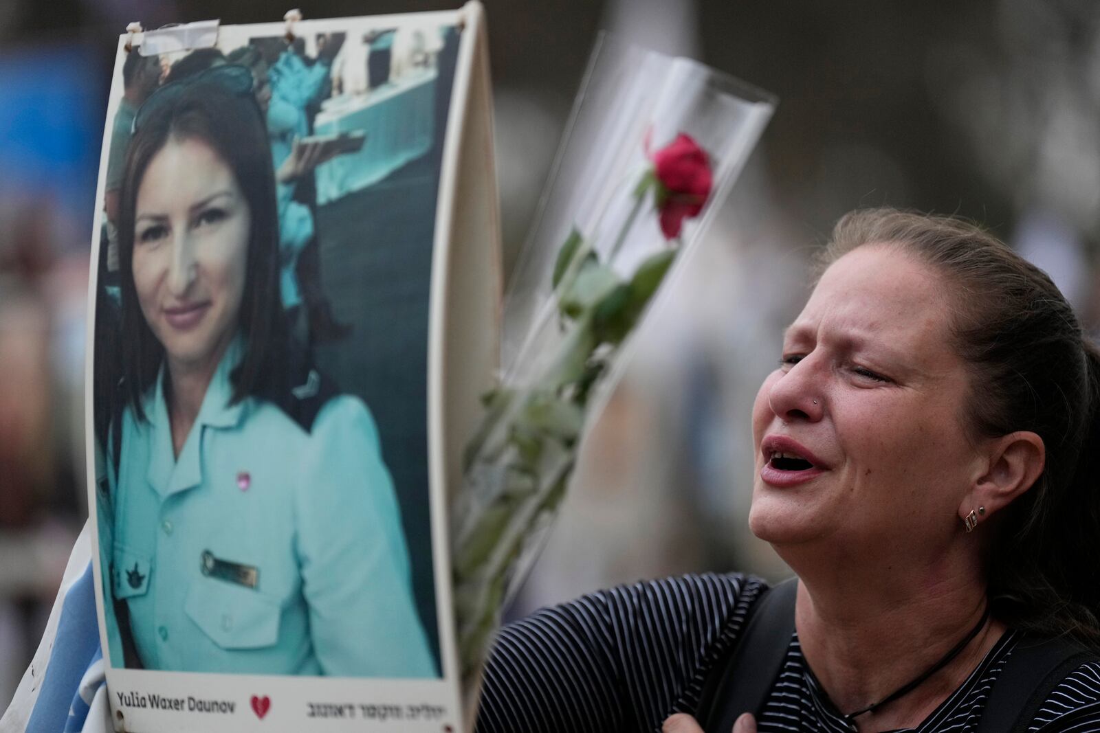 Victoria stands in front a picture of her sister, Yulia Waxer Daunt, as she visits the site of the Nova music festival, where hundreds of revelers were killed and abducted by Hamas and taken into Gaza, on the one-year anniversary of the attack, near Kibbutz Reim, southern Israel, Monday, Oct. 7, 2024. (AP Photo/Ariel Shalit)