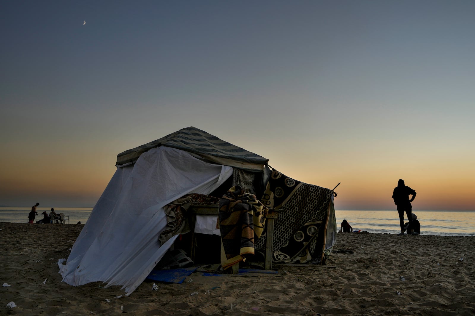 A displaced family stand next to their tent as a temporary shelter at Ramlet al-Baida public beach, after fleeing the Israeli airstrikes in the south, in Beirut, Lebanon, Tuesday, Oct. 8, 2024. (AP Photo/Bilal Hussein)