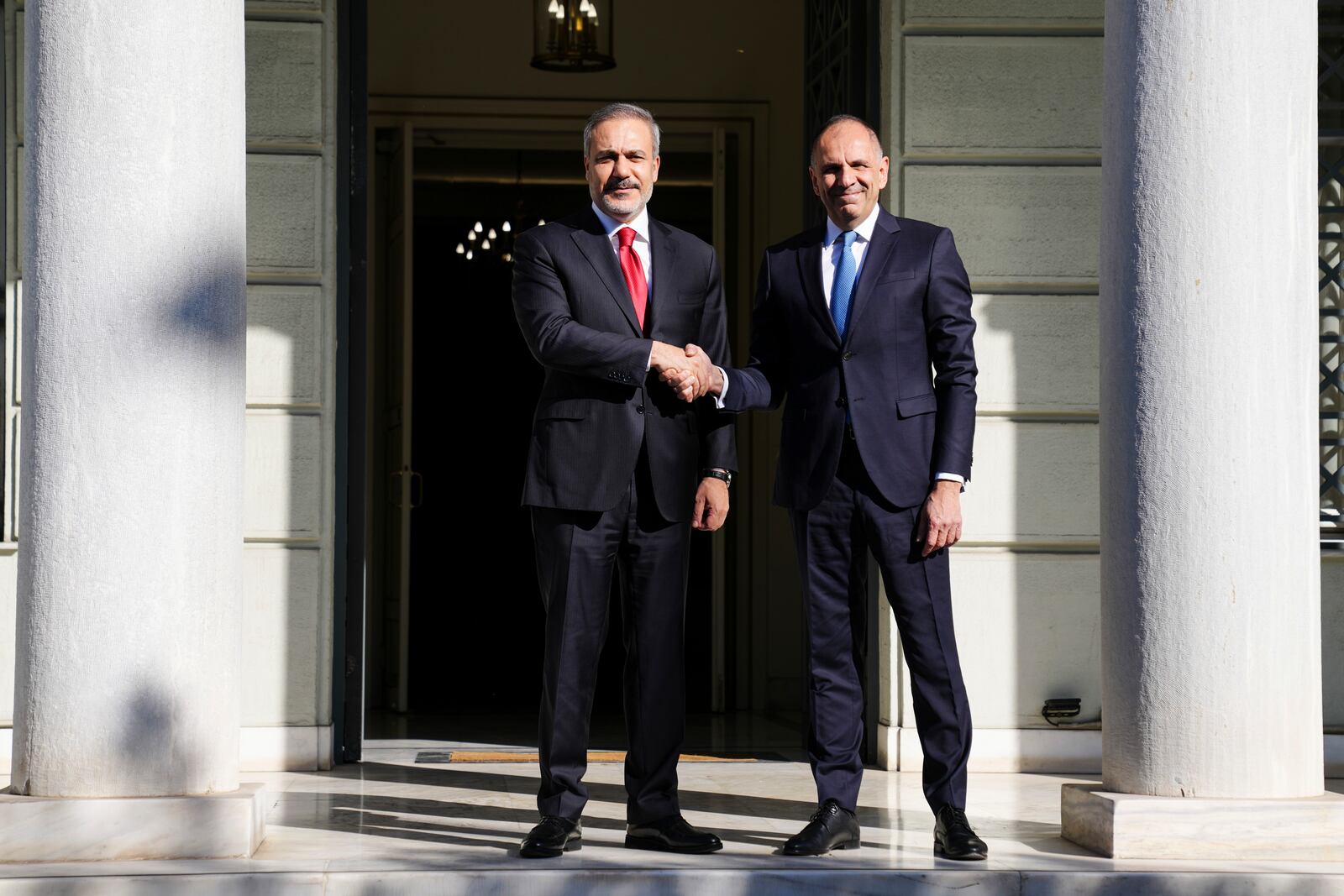 Greek Foreign Minister George Gerapetritis, right, welcomes his Turkish counterpart Hakan Fidan before their meeting in Athens, Greece, Friday, Nov. 8, 2024. (AP Photo/Thanassis Stavrakis)