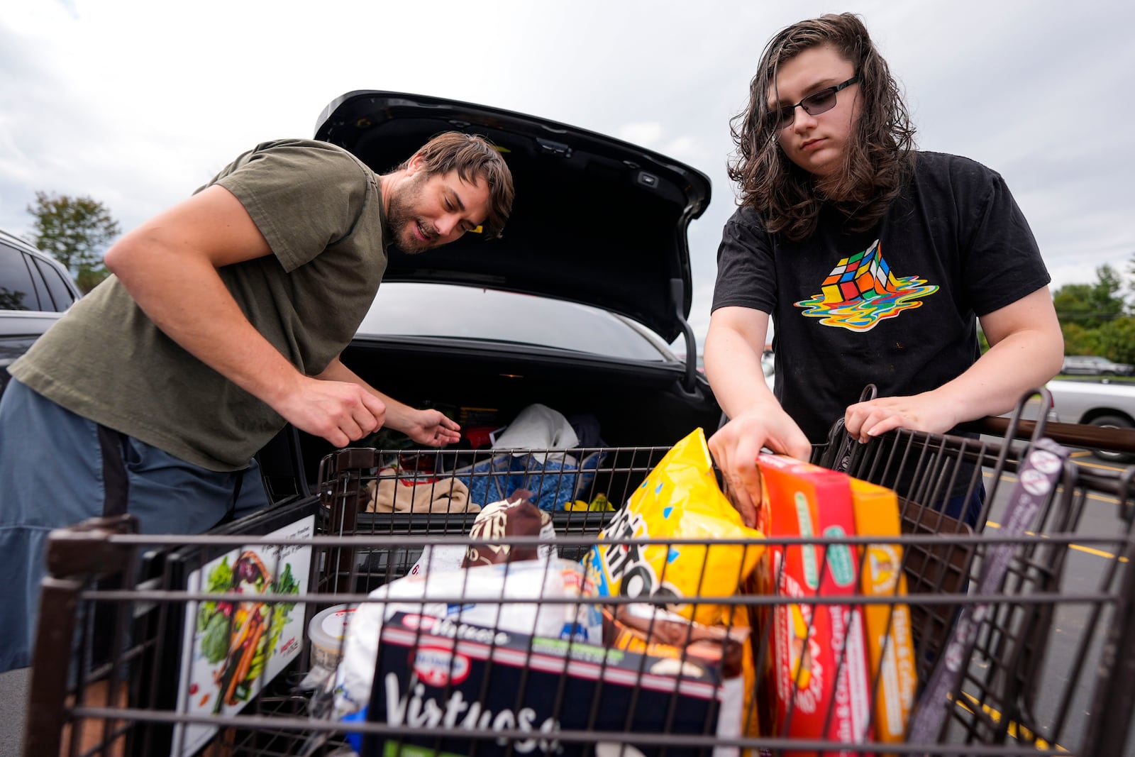 Drew Merritt, left, and Jeremy King load groceries after standing in line outside an Ingles grocery store in the aftermath of Hurricane Helene, Monday, Sept. 30, 2024, in Asheville, N.C. (AP Photo/Mike Stewart)