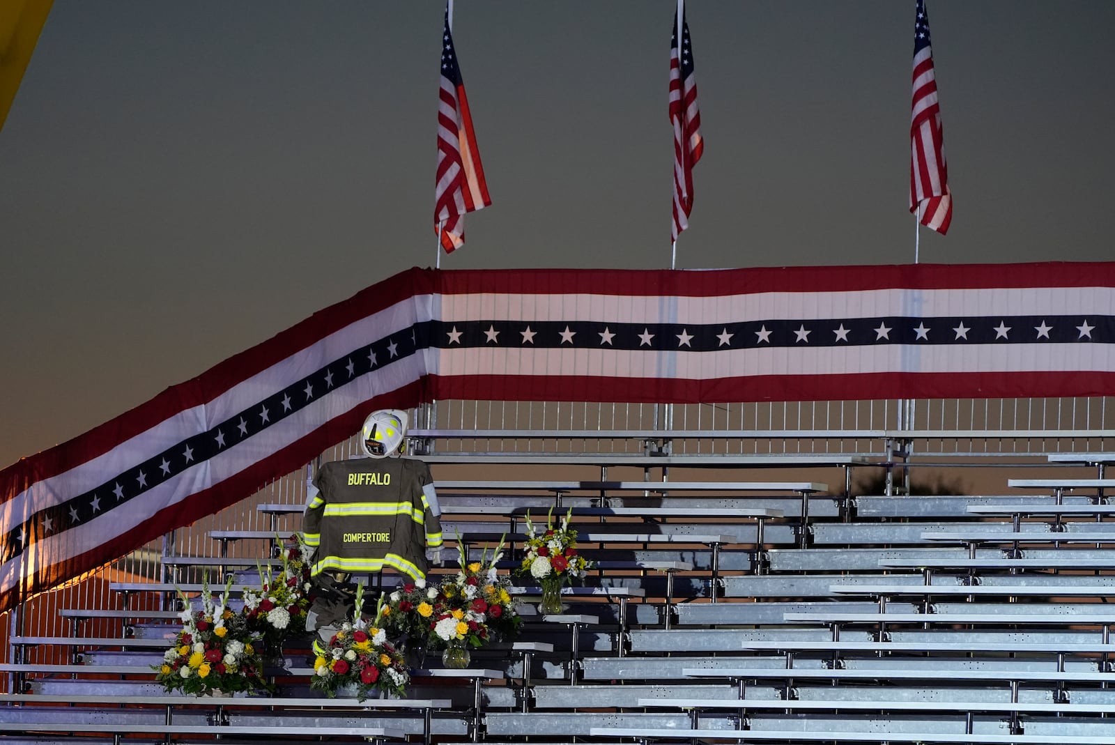 A memorial for firefighter Corey Comperatore, who died as he shielded family members from gunfire, is seen in the bleachers before Republican presidential nominee former President Donald Trump speaks at the Butler Farm Show, the site where a gunman tried to assassinate him in July, Saturday, Oct. 5, 2024, in Butler, Pa. (AP Photo/Alex Brandon)