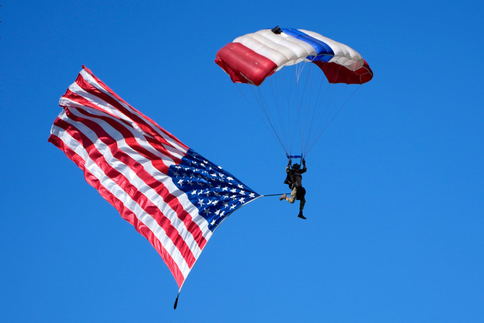 A parachuter with an American flag descends over a campaign event for Republican presidential nominee former President Donald Trump at the Butler Farm Show, Saturday, Oct. 5, 2024, in Butler, Pa. (AP Photo/Alex Brandon)