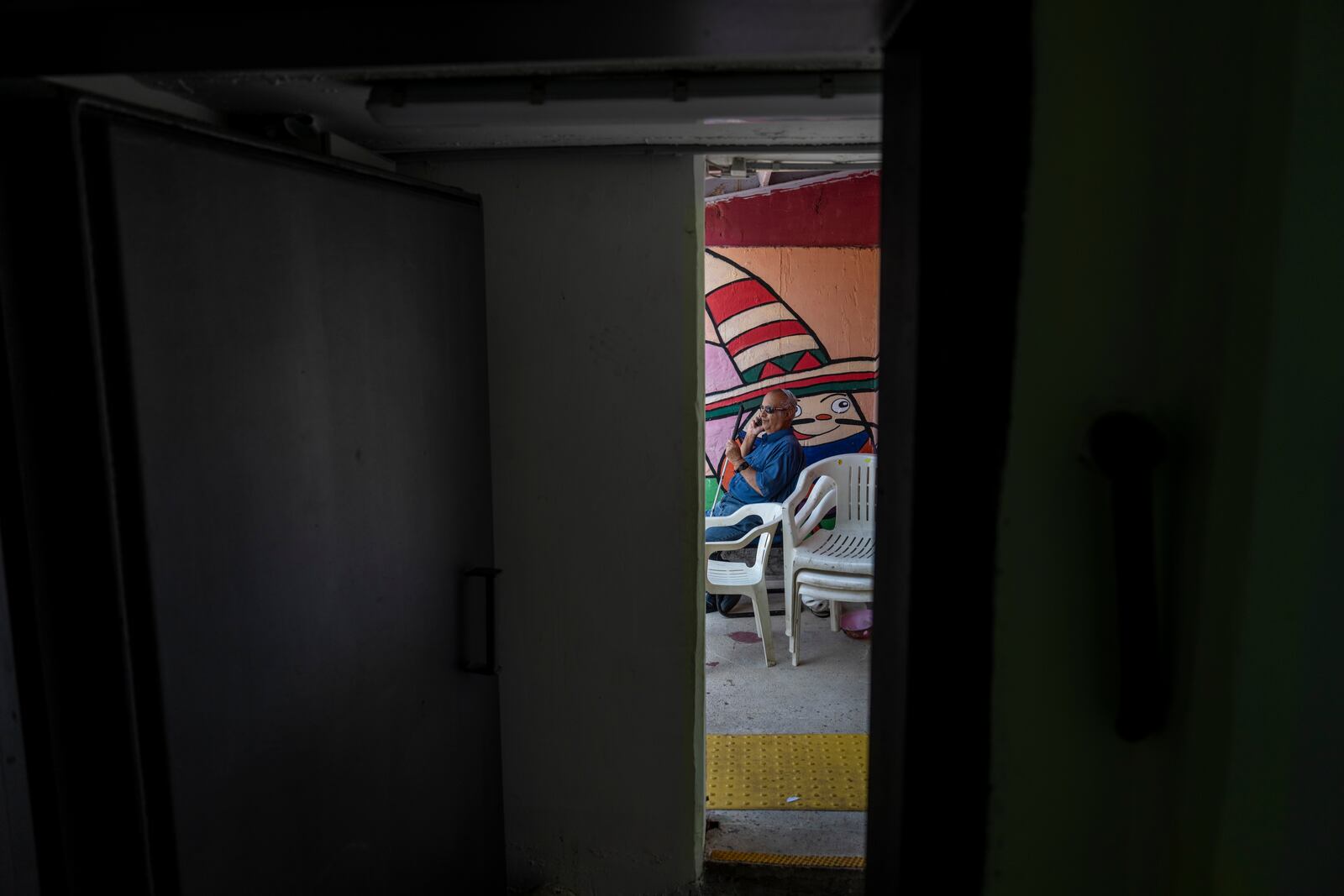 A man speaks on the phone in a public bomb shelter to stay safe from rockets fired from Lebanon in Acre, northern Israel, Sunday, Oct. 13, 2024. (AP Photo/Ariel Schalit)