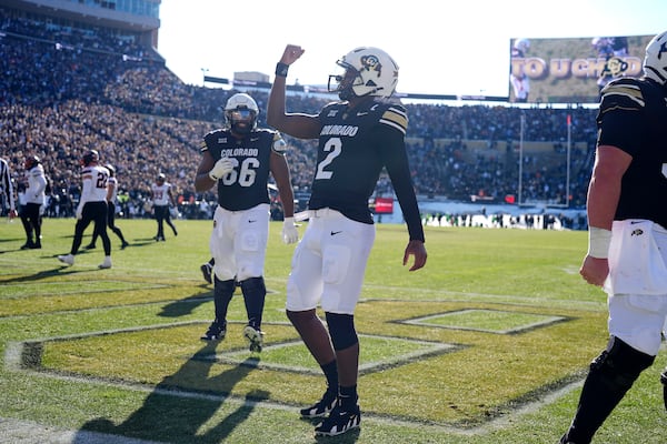 Colorado quarterback Shedeur Sanders, front, gestures after throwing a touchdown pass to wide receiver LaJohntay Wester as offensive lineman Justin Mayers looks on in the first half of an NCAA college football game against Oklahoma State Friday, Nov. 29, 2024, in Boulder, Colo. (AP Photo/David Zalubowski)