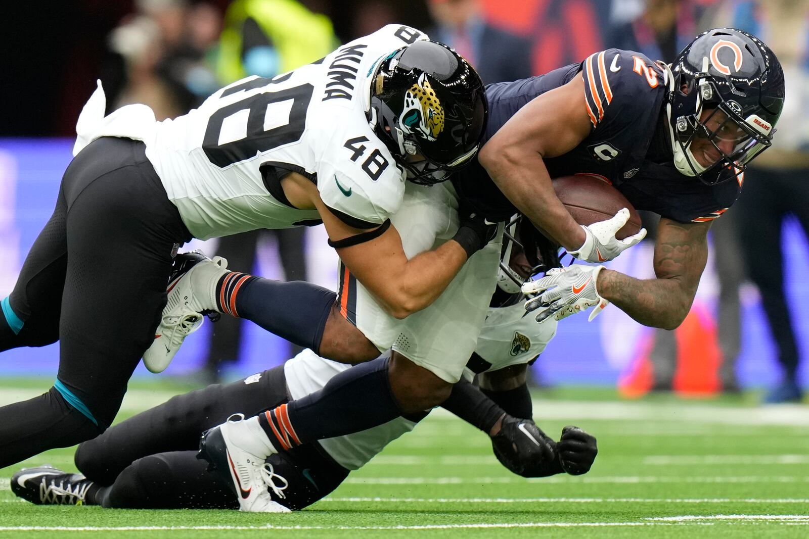 Chicago Bears wide receiver DJ Moore (2) is tackled by Jacksonville Jaguars linebacker Chad Muma (48) during an NFL football game at the Tottenham Hotspur stadium between the Jacksonville Jaguars and Chicago Bears in London, Sunday, Oct. 13, 2024. (AP Photo/Alastair Grant)