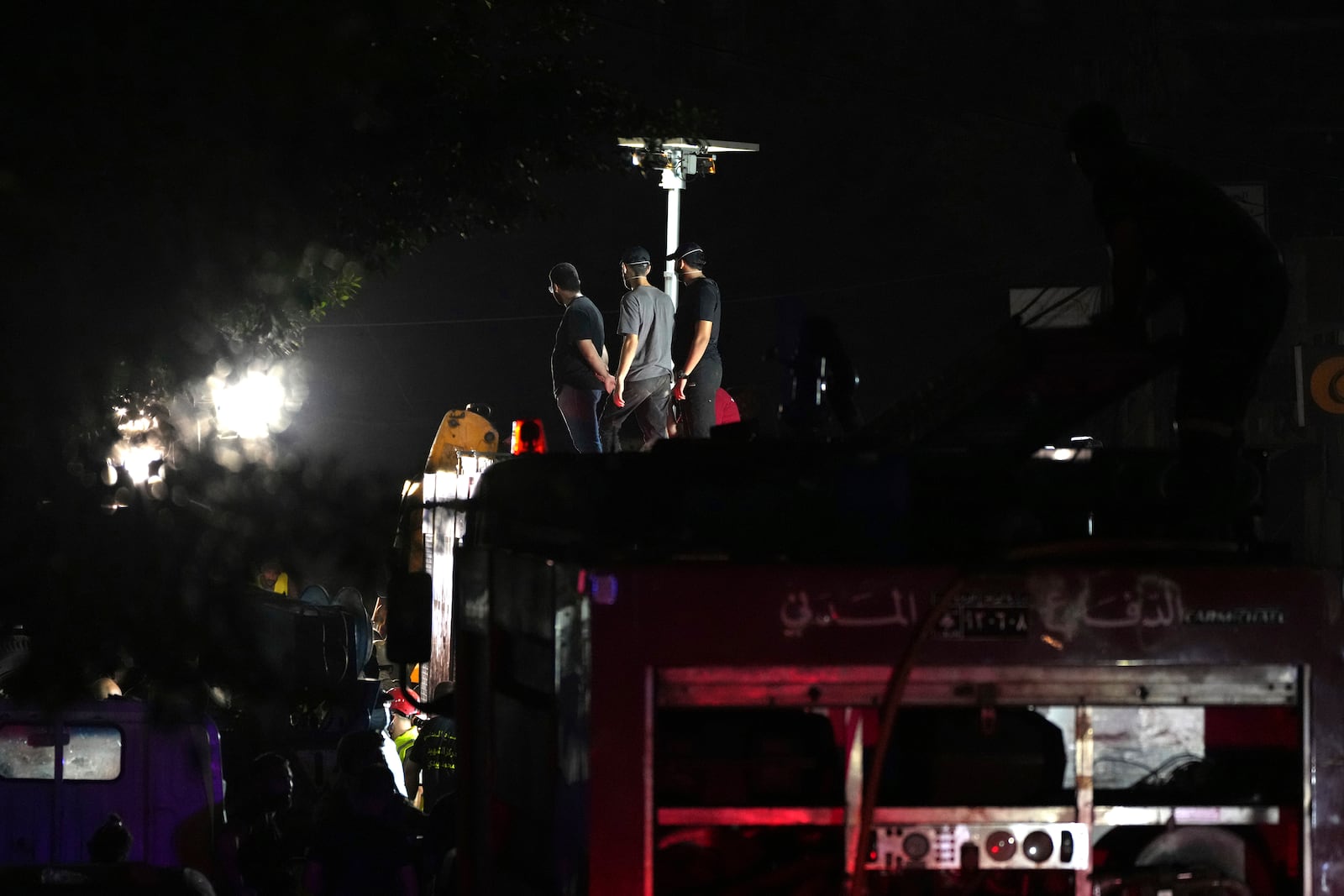 Members of Hezbollah stand on a fire truck as rescuers work at the scene of an Israeli missile strike in the southern suburbs of Beirut, Friday, Sept. 20, 2024. (AP Photo/Hassan Ammar)