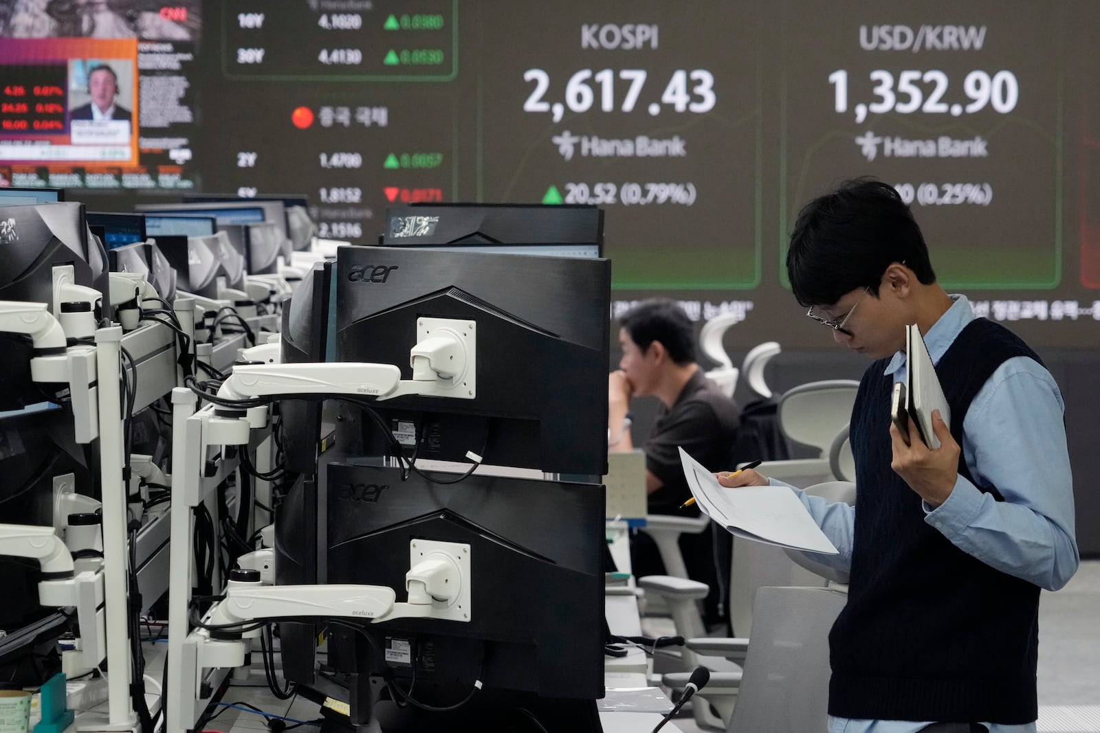 A currency trader reads documents at the foreign exchange dealing room of the KEB Hana Bank headquarters in Seoul, South Korea, Monday, Oct. 14, 2024. (AP Photo/Ahn Young-joon)