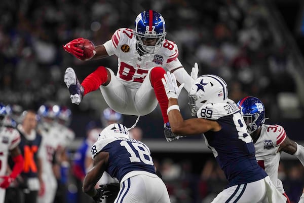 New York Giants wide receiver Ihmir Smith-Marsette (87) leaps over Dallas Cowboys' Damone Clark (18) and Brevyn Spann-Ford (89) on a punt return during the first half of an NFL football game in Arlington, Texas, Thursday, Nov. 28, 2024. (AP Photo/Tony Gutierrez)