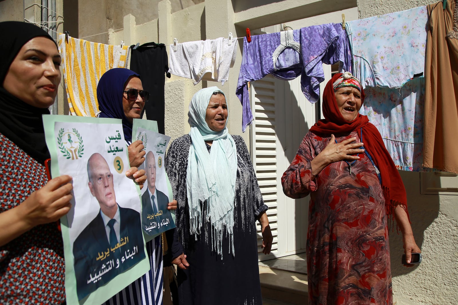 Supporters of Tunisian President and candidate for re-election Kais Saied meet with residents of a neighbourhood during a campaign tour, in Ariana, Tunisia, Thursday, Sept. 26, 2024. (AP Photo/Anis Mili)