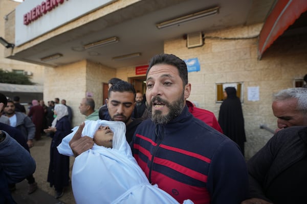 A man carries a dead child, one of the victims from an Israeli airstrike, outside a hospital in Deir al-Balah, Gaza, Sunday Nov. 17, 2024. Palestinian medical officials reported Sunday that Israeli strikes overnight killed 12 people in Central Gaza. One child and five women were counted among them.(AP Photo/Abdel Kareem Hana)