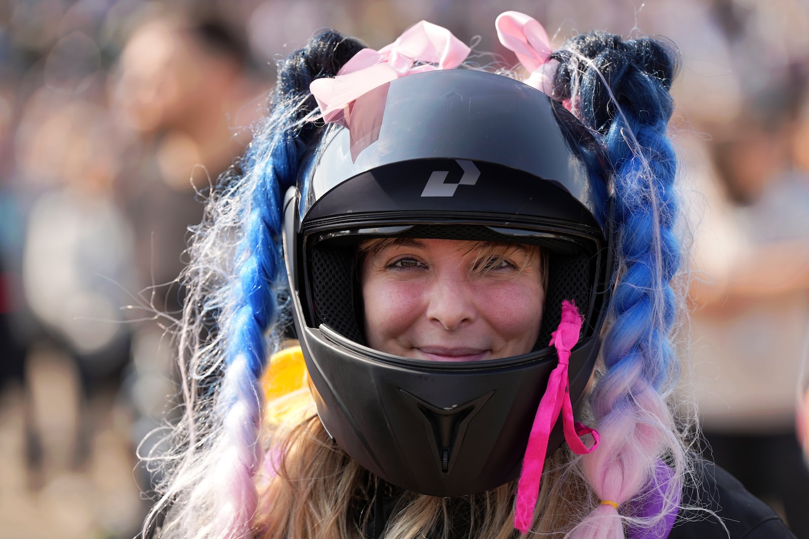 A woman wearing a decorated helmet arrives at the Roman Catholic holy shrine of Fatima to attend the IX Pilgrimage of the Blessing of Helmets that draws tens of thousands, in Fatima, Portugal, Sunday, Sept. 22, 2024. (AP Photo/Ana Brigida)