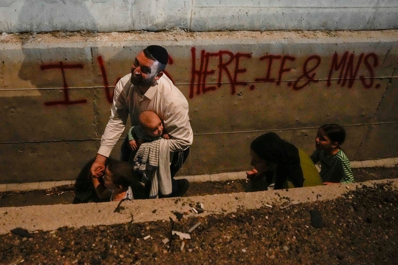 People take cover on the side of the road as a siren sounds a warning of incoming missiles on a freeway in Shoresh, Israel Tuesday, Oct. 1, 2024. (AP Photo/Ohad Zwigenberg)