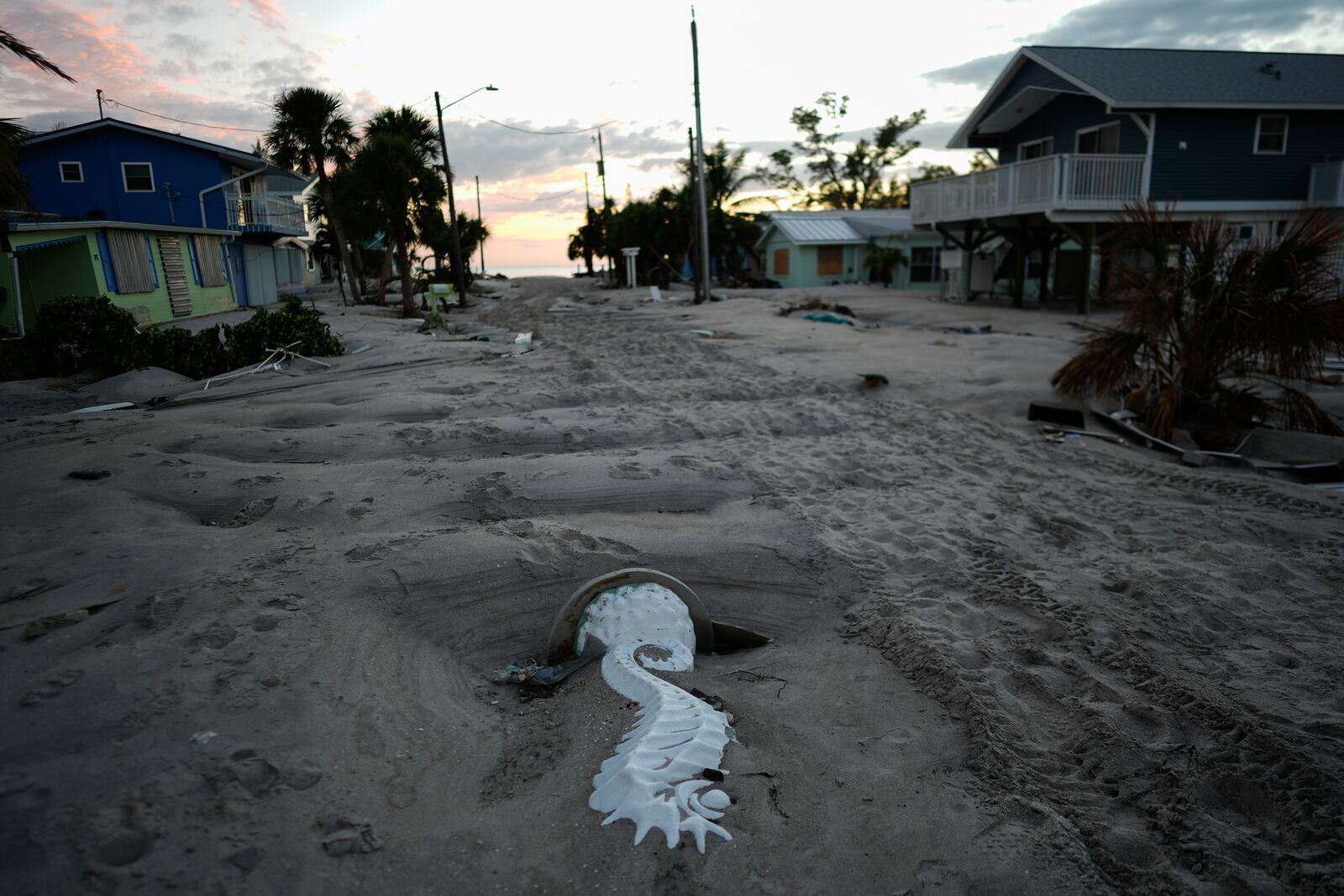 A seahorse statue lies embedded in feet of sand covering a road on Manasota Key, Fla., following the passage of Hurricane Milton, Saturday, Oct. 12, 2024. (AP Photo/Rebecca Blackwell)