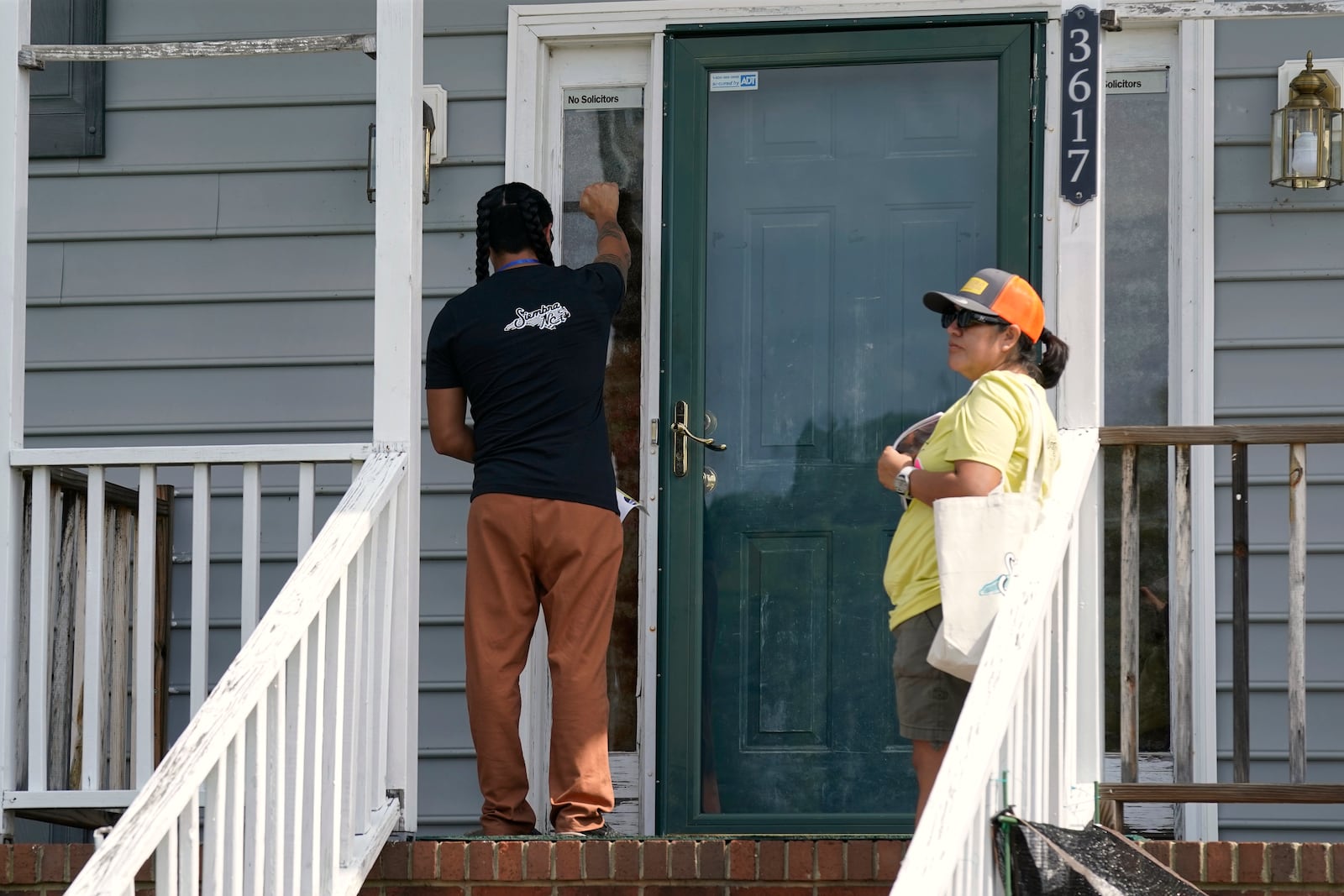 Salvador Fonseca, left, and Elena Jimenez knock on the door of a home during a voter engagement event for the Latino community in Greensboro, N.C., Saturday, Sept. 21, 2024. (AP Photo/Chuck Burton)