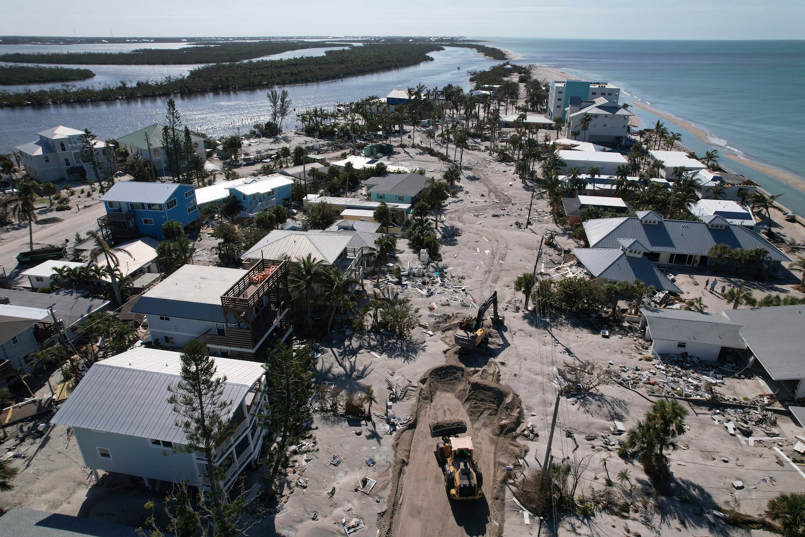 Charlotte County workers clear feet of sand from the main road on southern Manasota Key, in Englewood, Fla., following the passage of Hurricane Milton, Sunday, Oct. 13, 2024. (AP Photo/Rebecca Blackwell)