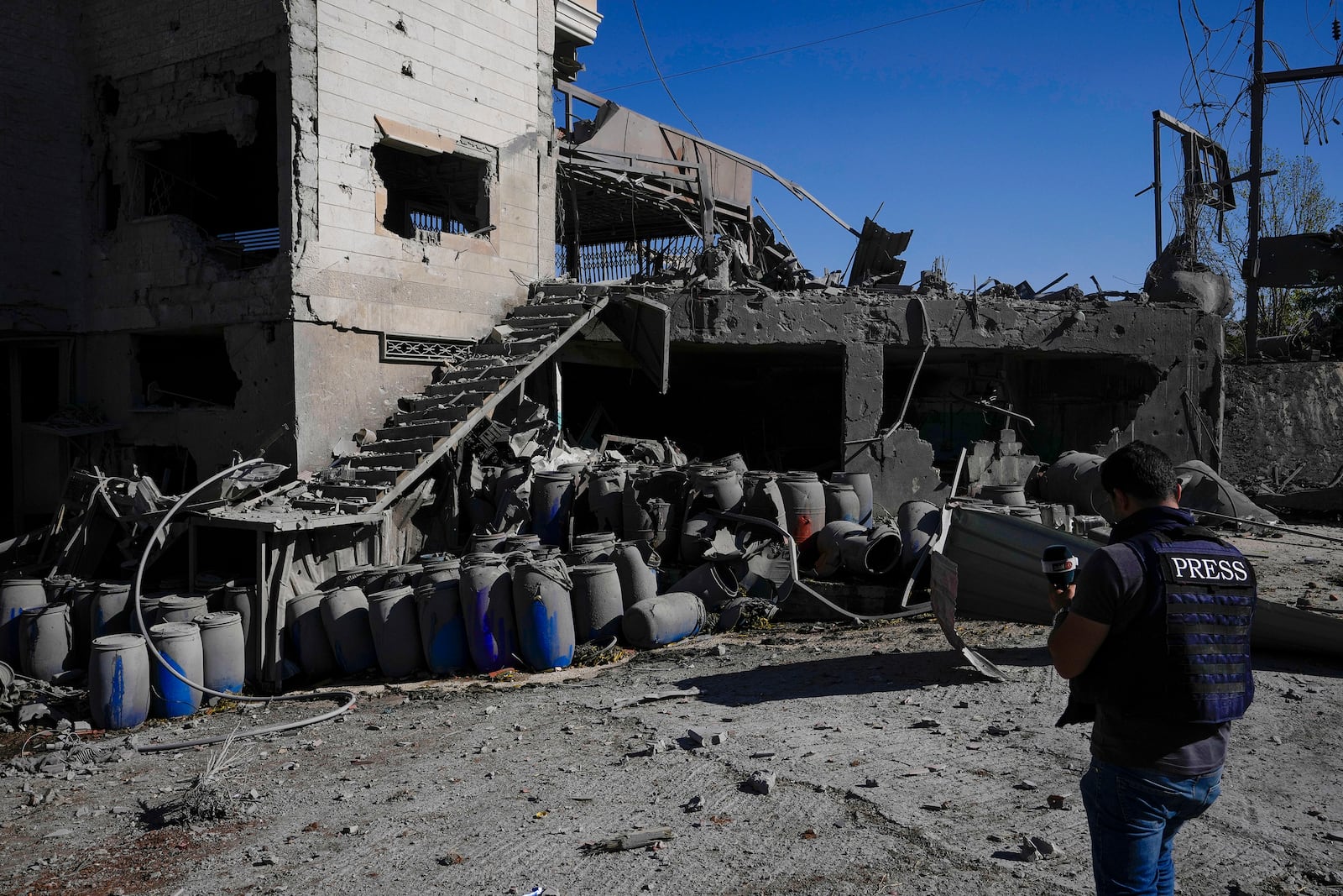 A journalist documents the damaged buildings at the site of an Israeli airstrike, in the village of Temnin, Bekaa Valley, eastern Lebanon, Saturday, Oct. 5, 2024. (AP Photo/Hassan Ammar)