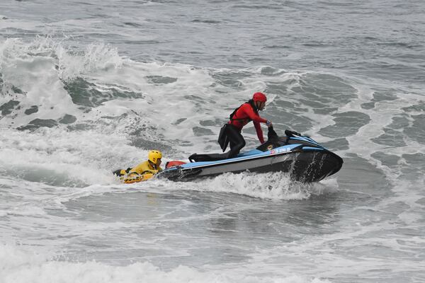 CORRECTS DAY: Lifeguards look for survivors after a boat capsized in the surf Monday, May. 5, 2025, in at Torrey Pines State beach in San Diego, Calif. (AP Photo/Denis Poroy)