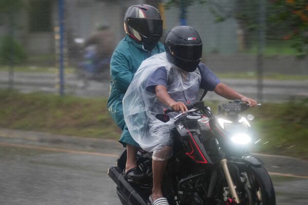 Motorcyclists cover themselves with plastic sheets during rains brought on by tropical storm Sara in San Pedro Sula, Honduras, Friday, Nov. 15, 2024. (AP Photo/Moises Castillo)