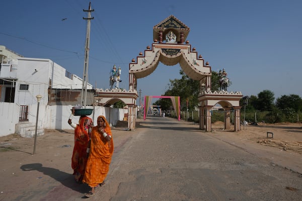 Women walks past an entrance gate of Dingucha village in Gandhinagar, India, Tuesday, Nov. 12, 2024. (AP Photo/Ajit Solanki)