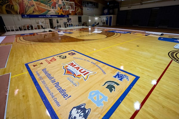 Workers set up banners and signs at Lahaina Civic Center, the venue for the Maui Invitational, Monday, Nov. 18, 2024, in Lahaina, Hawaii. The Maui Invitational is back in Lahaina, where eight of the NCAA's top men's basketball teams will compete in a three-day tournament. (AP Photo/Mengshin Lin)