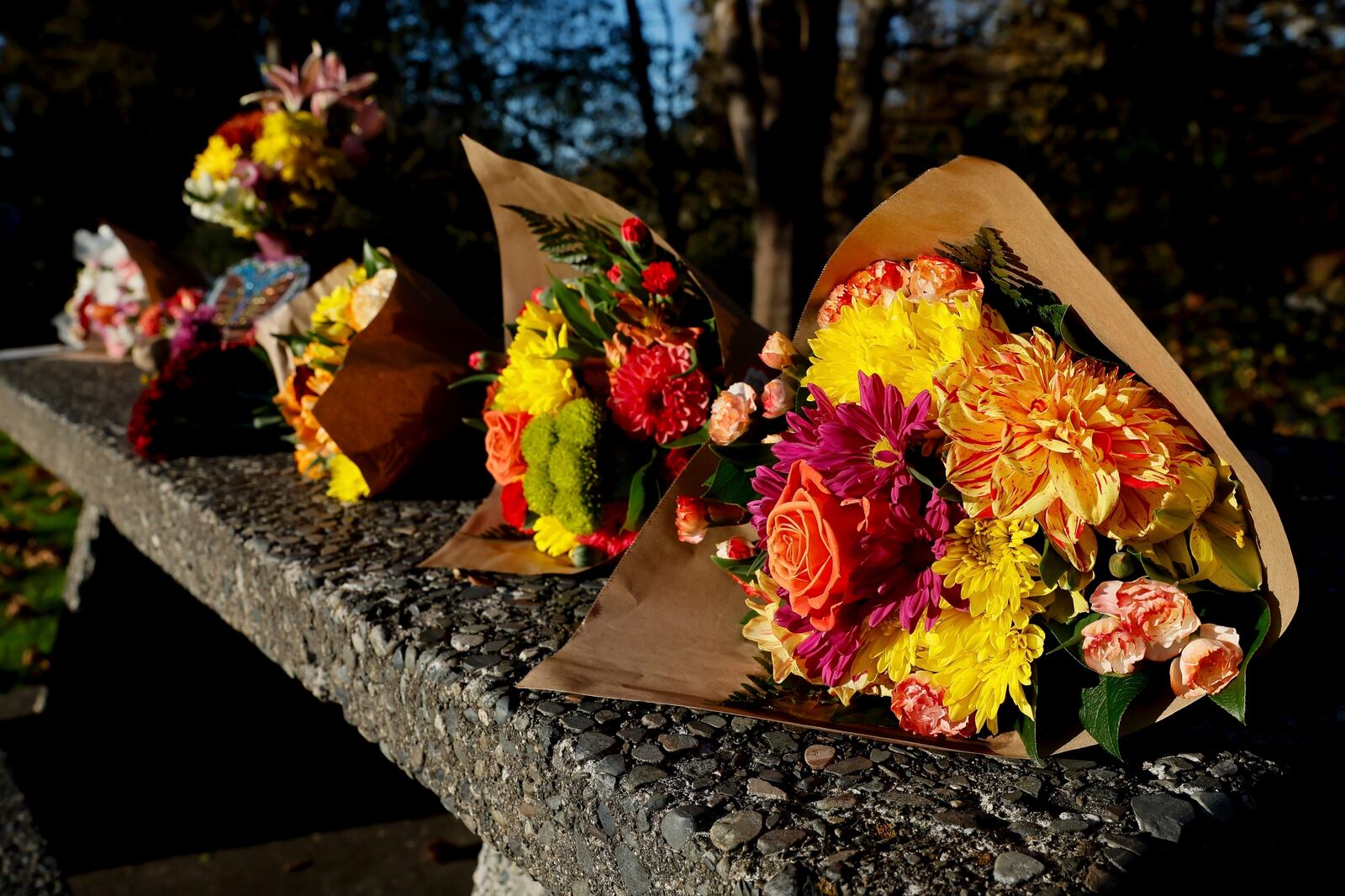 FILE- Bouquets of flowers line a stone picnic table at a roadside park as a small memorial to the victims of a mass shooting the day before in Fall City, Wash., Tuesday, Oct. 22, 2024. (Jennifer Buchanan/The Seattle Times via AP, File)