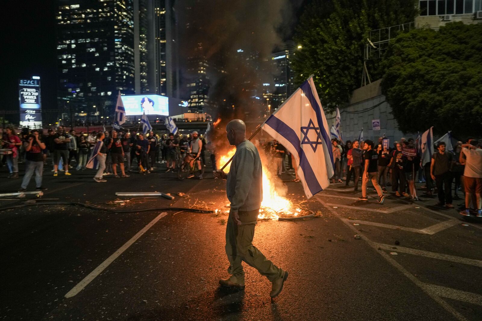 Israelis light a bonfire during a protest after Prime Minister Benjamin Netanyahu has dismissed his popular defense minister Yoav Gallant, in Tel Aviv, Israel, Tuesday, Nov. 5, 2024. (AP Photo/Oded Balilty)