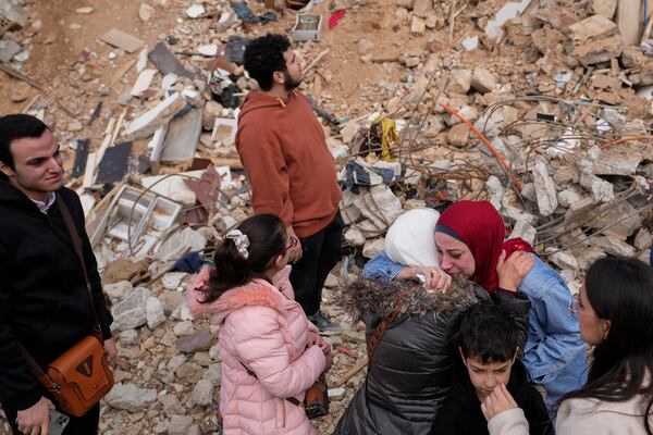 Displaced residents pause and hug as they stand in front of the rubble of their destroyed house in Baalbek, eastern Lebanon, Thursday, Nov. 28, 2024. (AP Photo/Hassan Ammar)