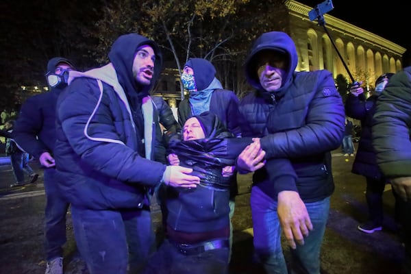 Protesters help a wounded person due to clashing with police after protesters pouring into the streets following Georgian Prime Minister Irakli Kobakhidze's announcement, rallying outside the parliament building in Tbilisi, Georgia, on Friday, Nov. 29, 2024. (AP Photo/Zurab Tsertsvadze)