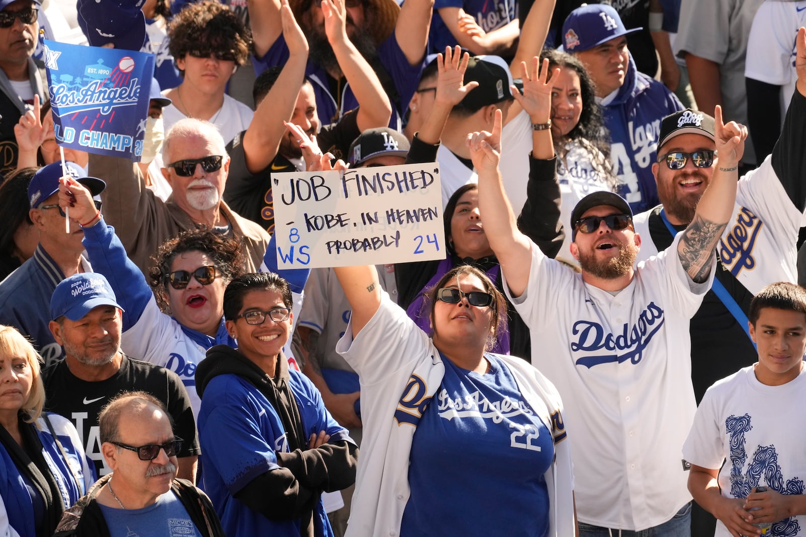 Fans cheer and hold signs before the Los Angeles Dodgers baseball World Series championship parade Friday, Nov. 1, 2024, in Los Angeles. (AP Photo/Damian Dovarganes)