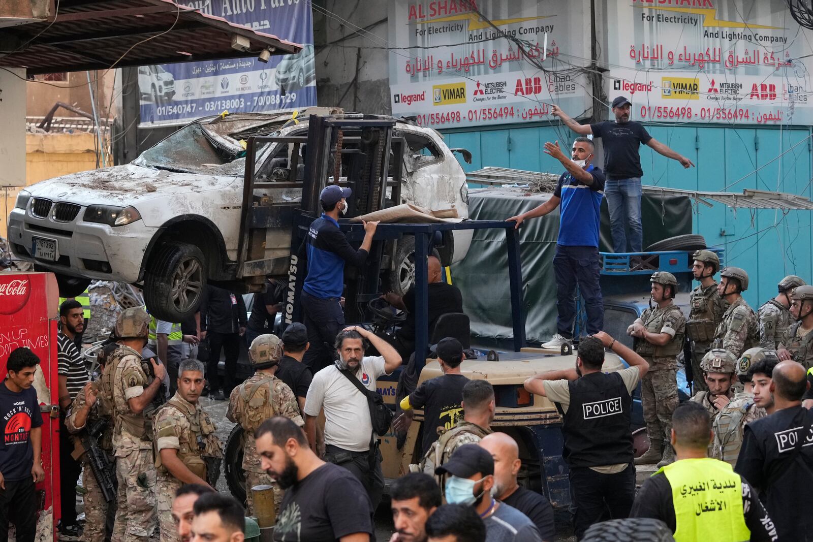 A forklift removes a damaged car as Lebanese army and emergency workers gather at the scene of an Israeli airstrike in Beirut's southern suburbs, Tuesday, Sept. 24, 2024. (AP Photo/Hassan Ammar)