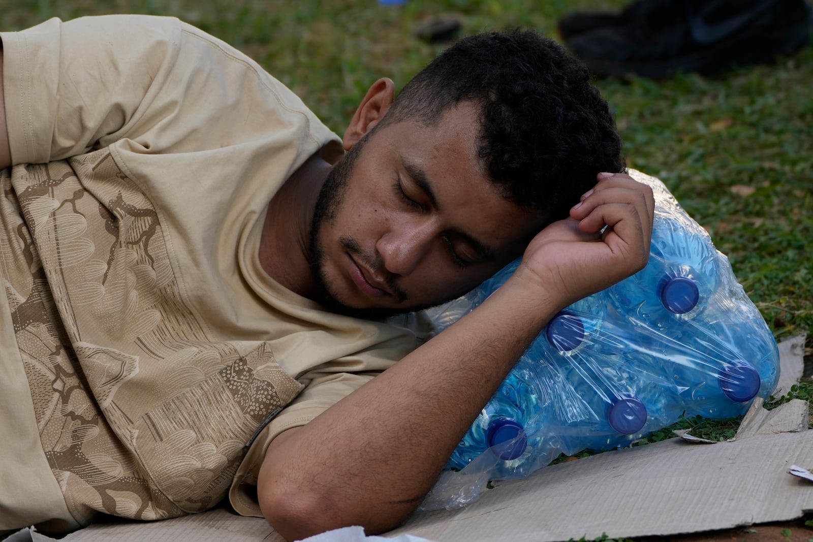 A man who fled the southern suburb of Beirut amid ongoing Israeli airstrikes, sleeps on bottles of water at a park in down town Beirut, Lebanon, Saturday, Sept. 28, 2024. (AP Photo/Hussein Malla)