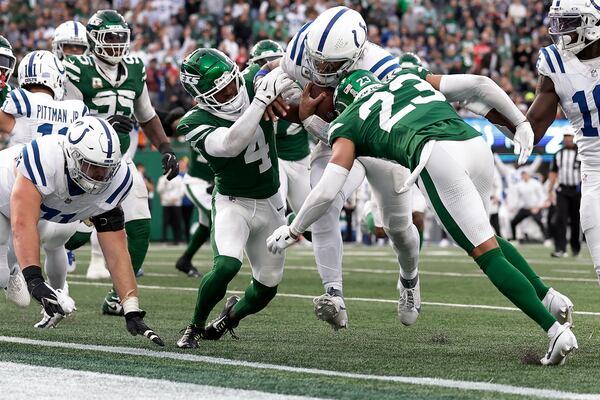 Indianapolis Colts quarterback Anthony Richardson (5) breaks through tackles by New York Jets cornerback Isaiah Oliver (23) and cornerback D.J. Reed (4) to score a touchdown during the fourth quarter of an NFL football game, Sunday, Nov. 17, 2024, in East Rutherford, N.J. (AP Photo/Adam Hunger)