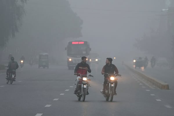 Vehicles and motorcyclists move with headlights on due to reduced visibility caused by smog enveloping the area of Lahore, Pakistan, Wednesday, Nov. 13, 2024. (AP Photo/K.M. Chaudary)