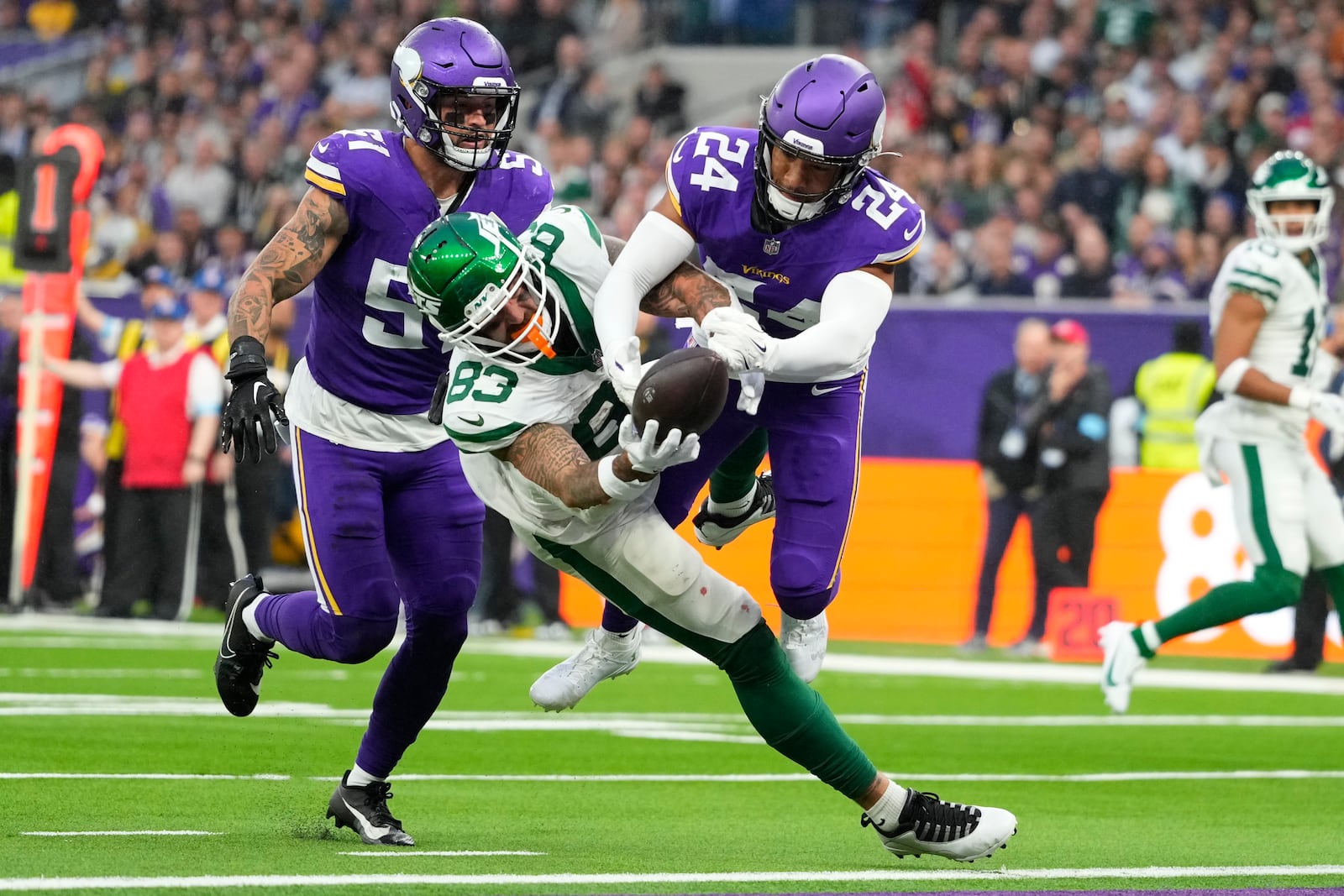 Minnesota Vikings' Camryn Bynum (24), right, fights for the ball with New York Jets' Tyler Conklin (83), center, during the second half of an NFL football game, Sunday, Oct. 6, 2024, at the Tottenham Hotspur stadium in London. (AP Photo/Kirsty Wigglesworth)