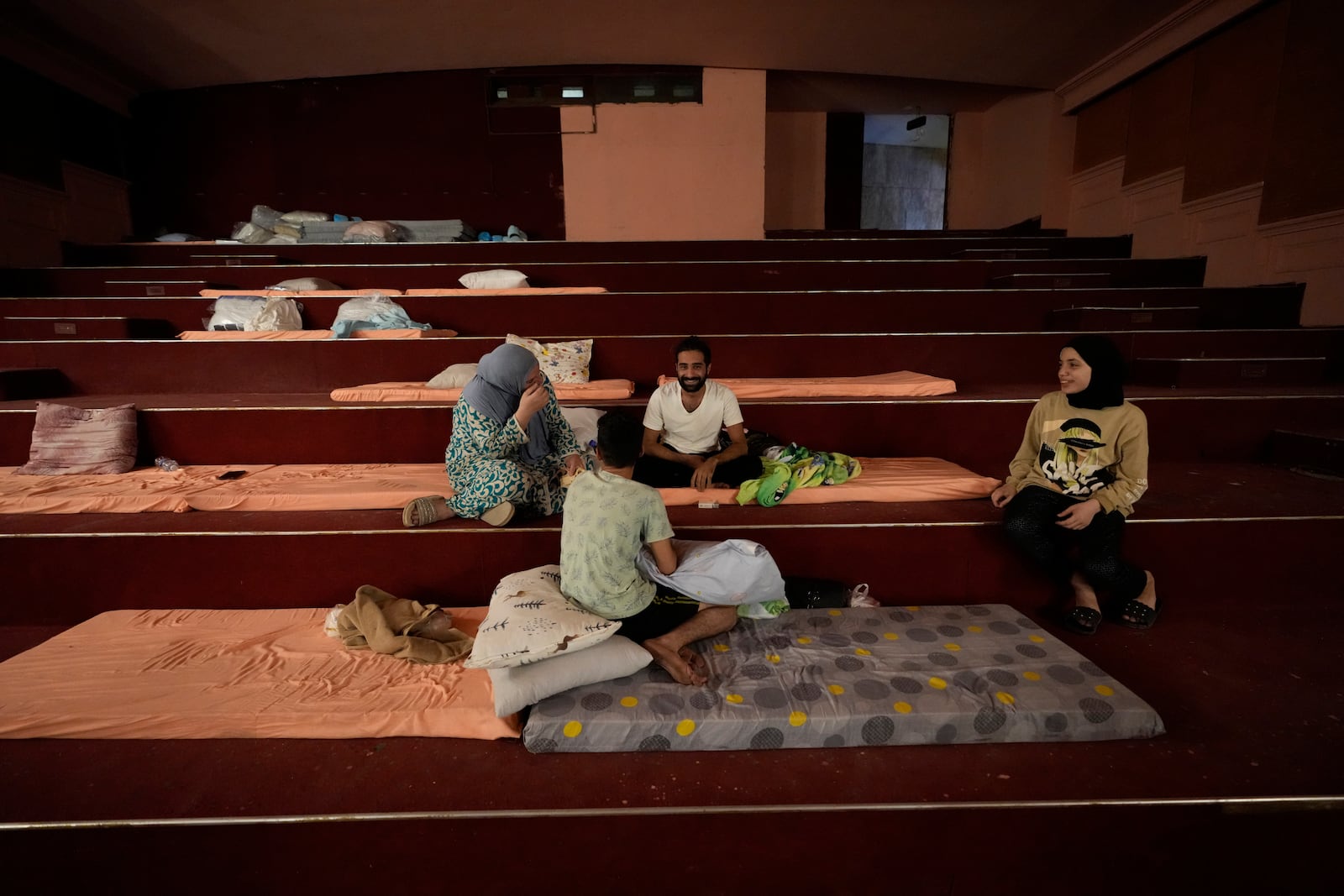 A displaced family, who fled the ongoing Hezbollah-Israel war in south Lebanon, sit on mattresses inside one of Beirut's oldest and best known movie theatres, Le Colisee, where they have taken shelter, in Beirut, Lebanon, Tuesday, Oct. 22, 2024. (AP Photo/Hussein Malla)