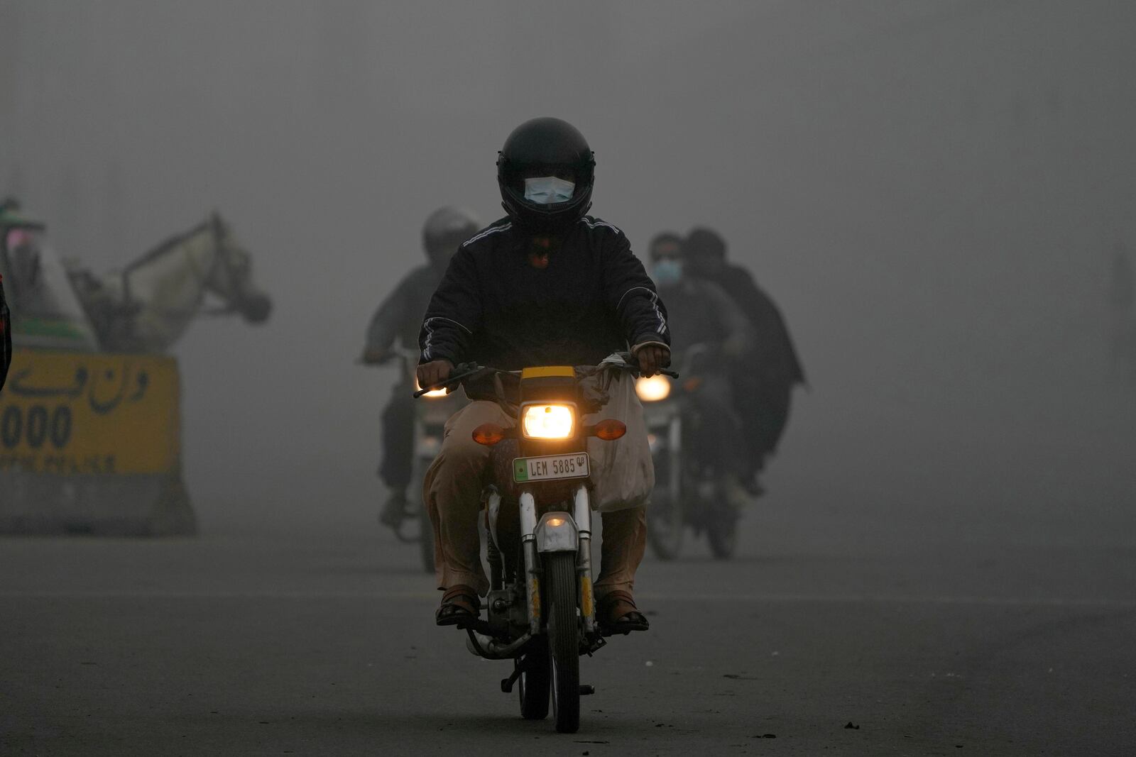 Motorcyclists move with headlights due to smog in Lahore, Pakistan, Friday, Nov. 8, 2024. (AP Photo/K.M. Chaudary)