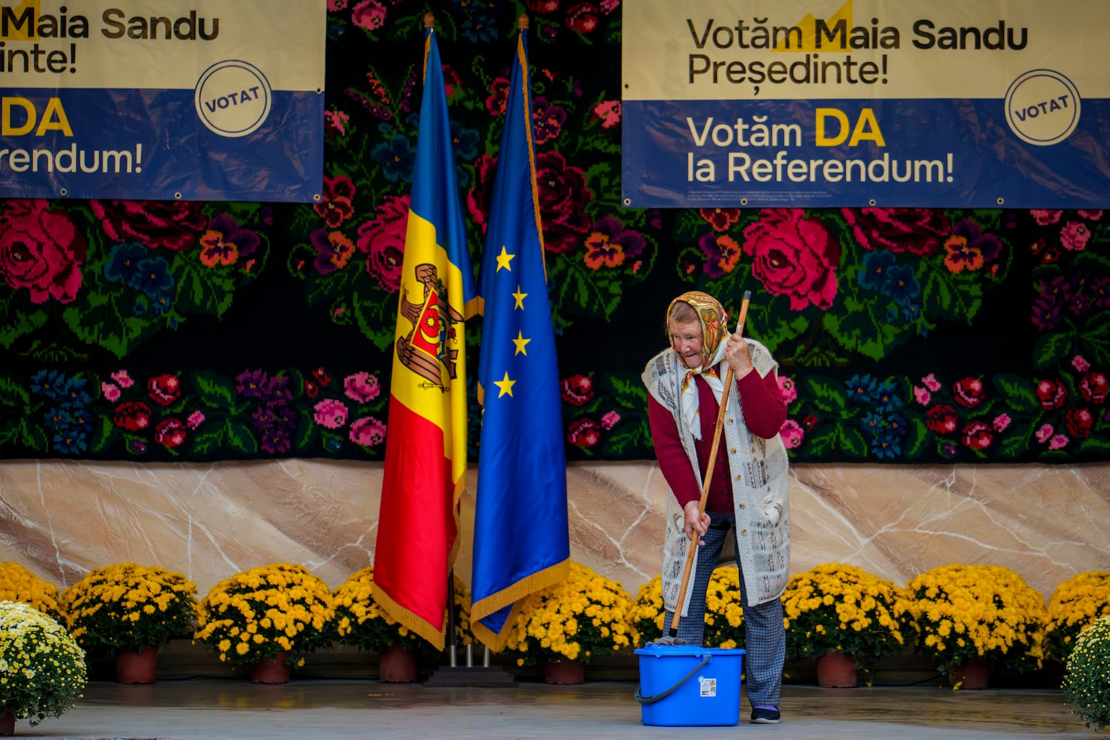 A woman mops a stage before an electoral rally of Moldova's President Maia Sandu in Magdacesti, Moldova, Thursday, Oct. 17, 2024, who is seeking a second term in office ahead of a presidential election and a referendum of whether to enshrine in Moldova's Constitution its path to European Union membership taking place on Oct. 20. (AP Photo/Vadim Ghirda)