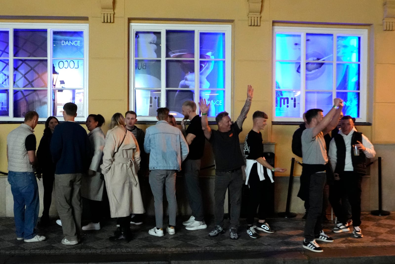 A group of tourists stand in line outside a bar as they attend a pub crawl tour in downtown Prague, Czech Republic, Thursday, Oct. 17, 2024. (AP Photo/Petr David Josek)