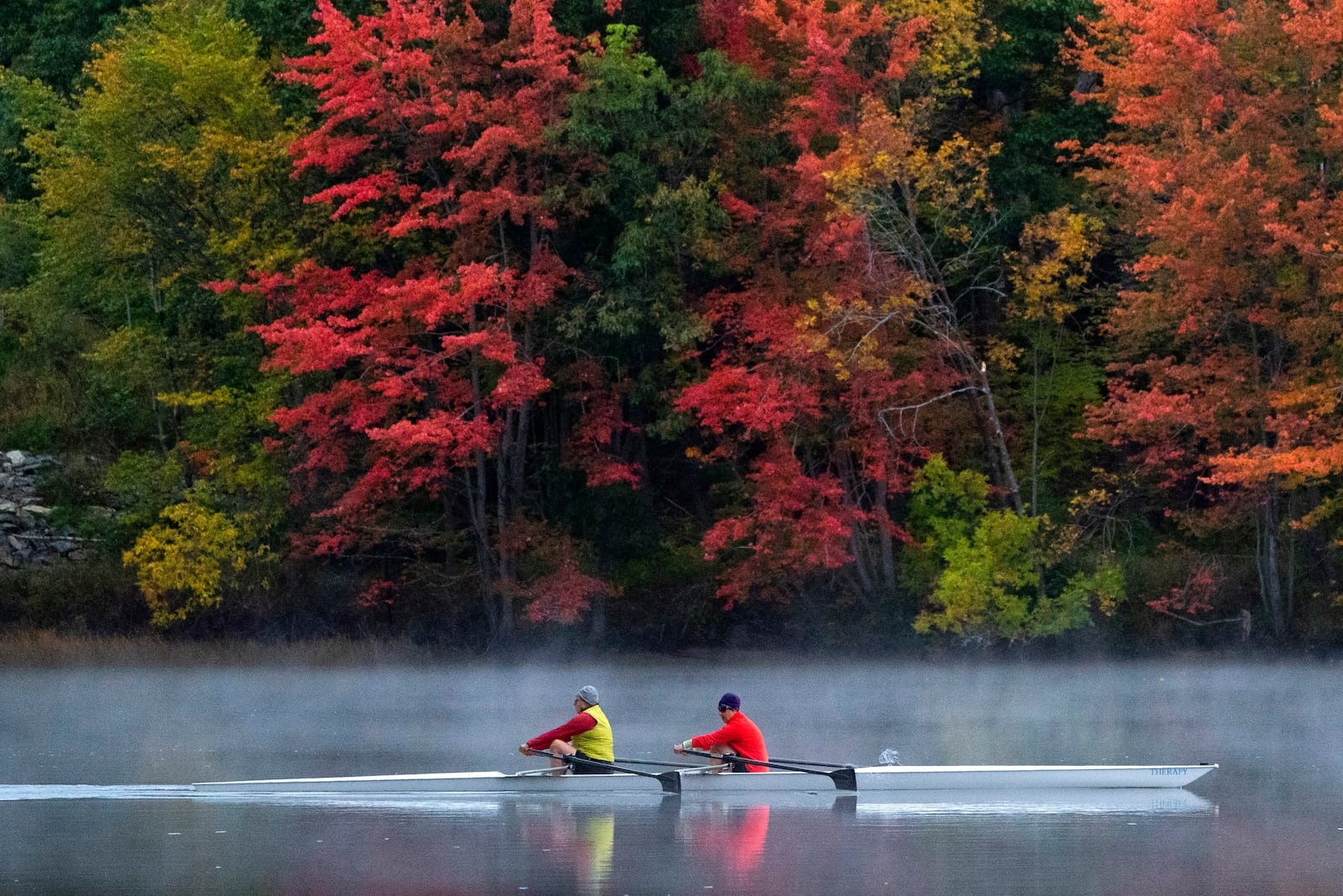 FILE - A pair of rowers glide on the Androscoggin River in Brunswick, Maine, where the foliage has changed to autumn colors, Oct. 10, 2021. (AP Photo/Robert F. Bukaty, File)