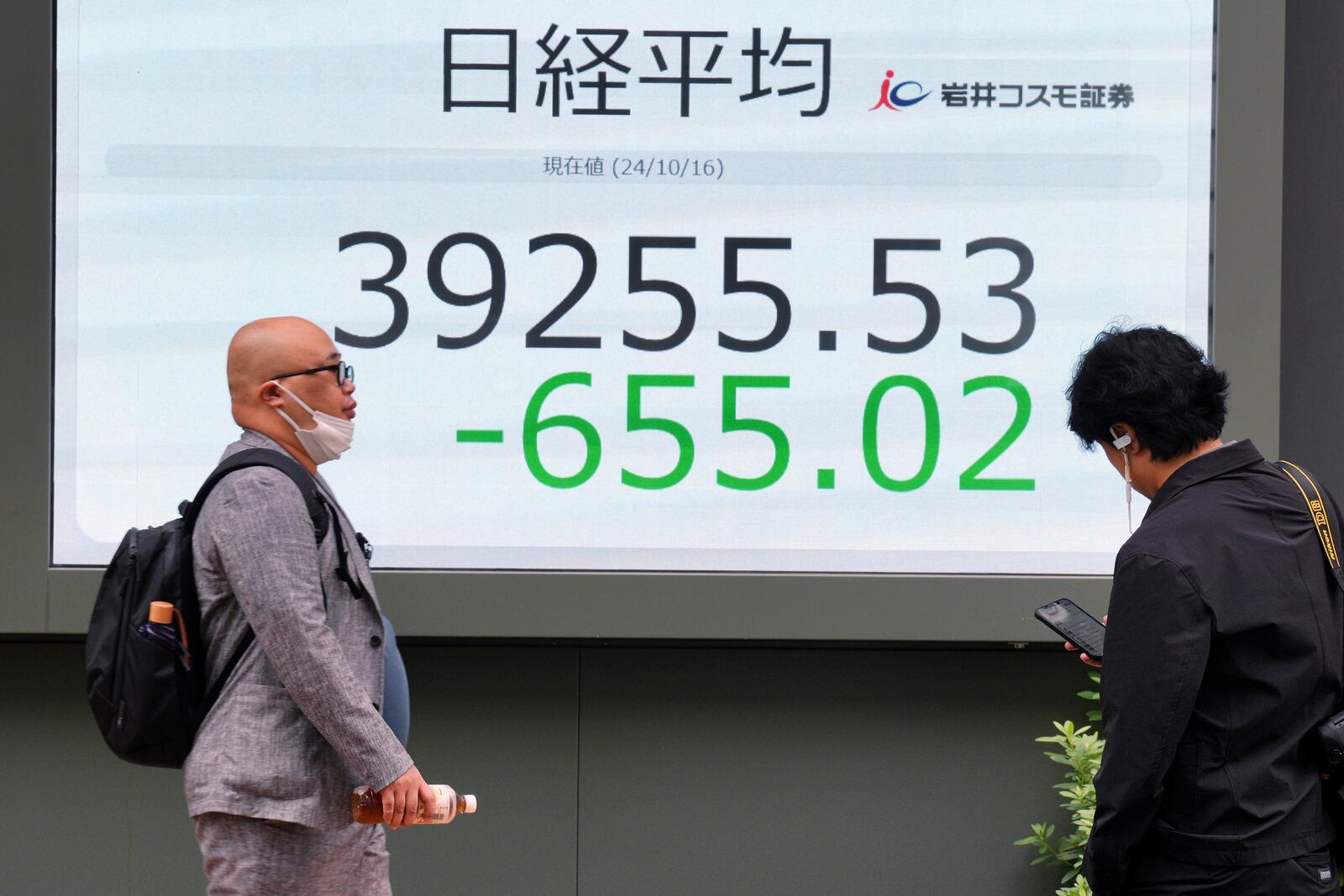 People walk in front of an electronic stock board showing Japan's Nikkei index at a securities firm Wednesday, Oct. 16, 2024, in Tokyo. (AP Photo/Eugene Hoshiko)