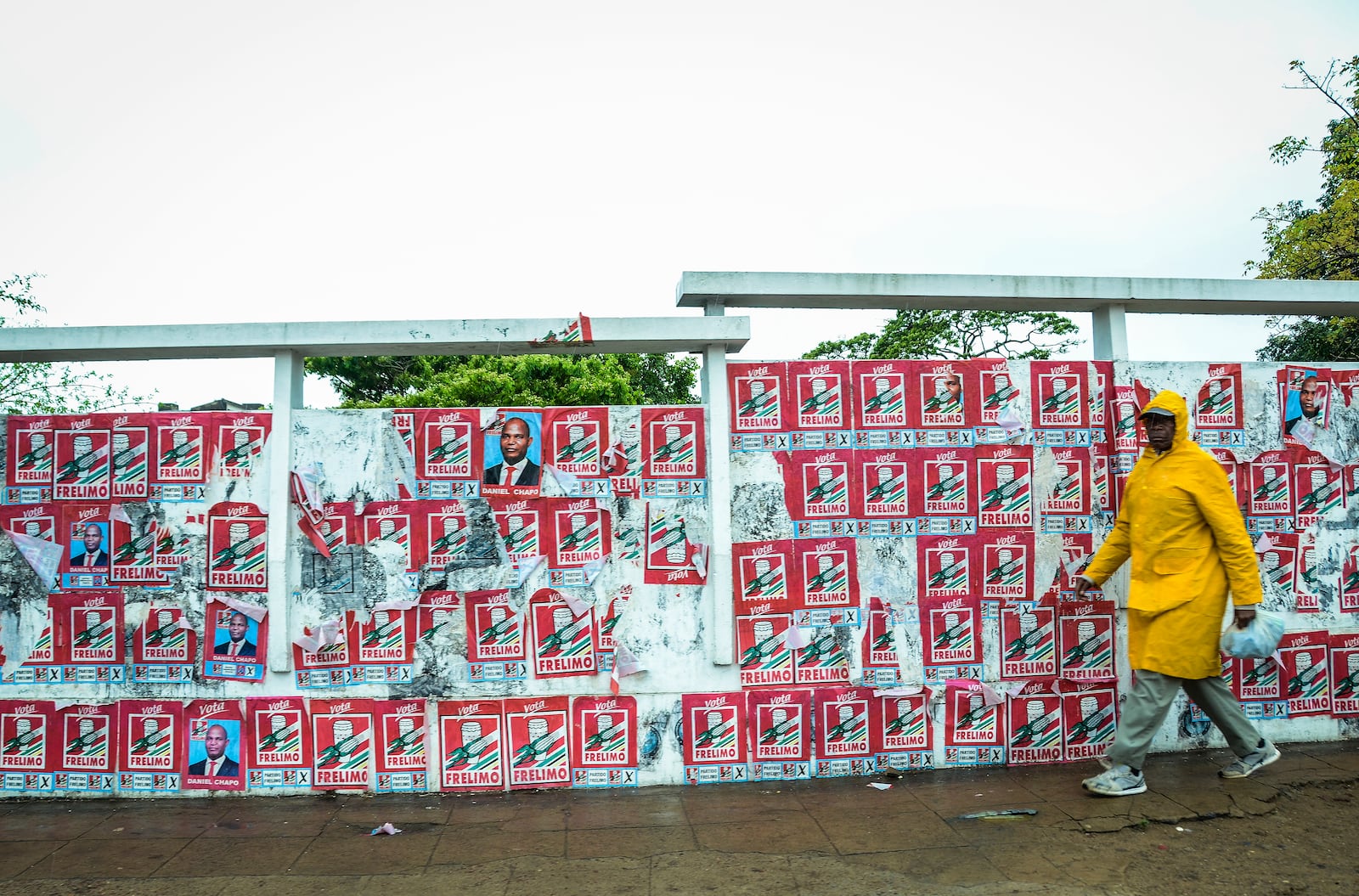 A pedestrian passes a wall of election posters in Maputo, Sunday, Oct. 6, 2024, ahead of elections to be held in Mozambique. (AP Photo/Carlos Uqueio)