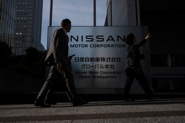 Visitors walk past Nissan signage at Nissan headquarters in Yokohama, Tuesday, May 13, 2025. (AP Photo/Louise Delmotte)