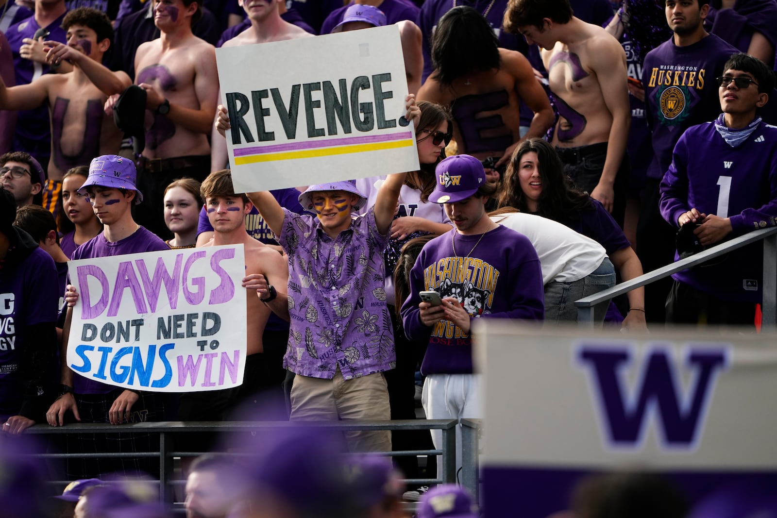 Washington fans hold signs before an NCAA college football game between Washington and Michigan, Saturday, Oct. 5, 2024, in Seattle. (AP Photo/Lindsey Wasson)