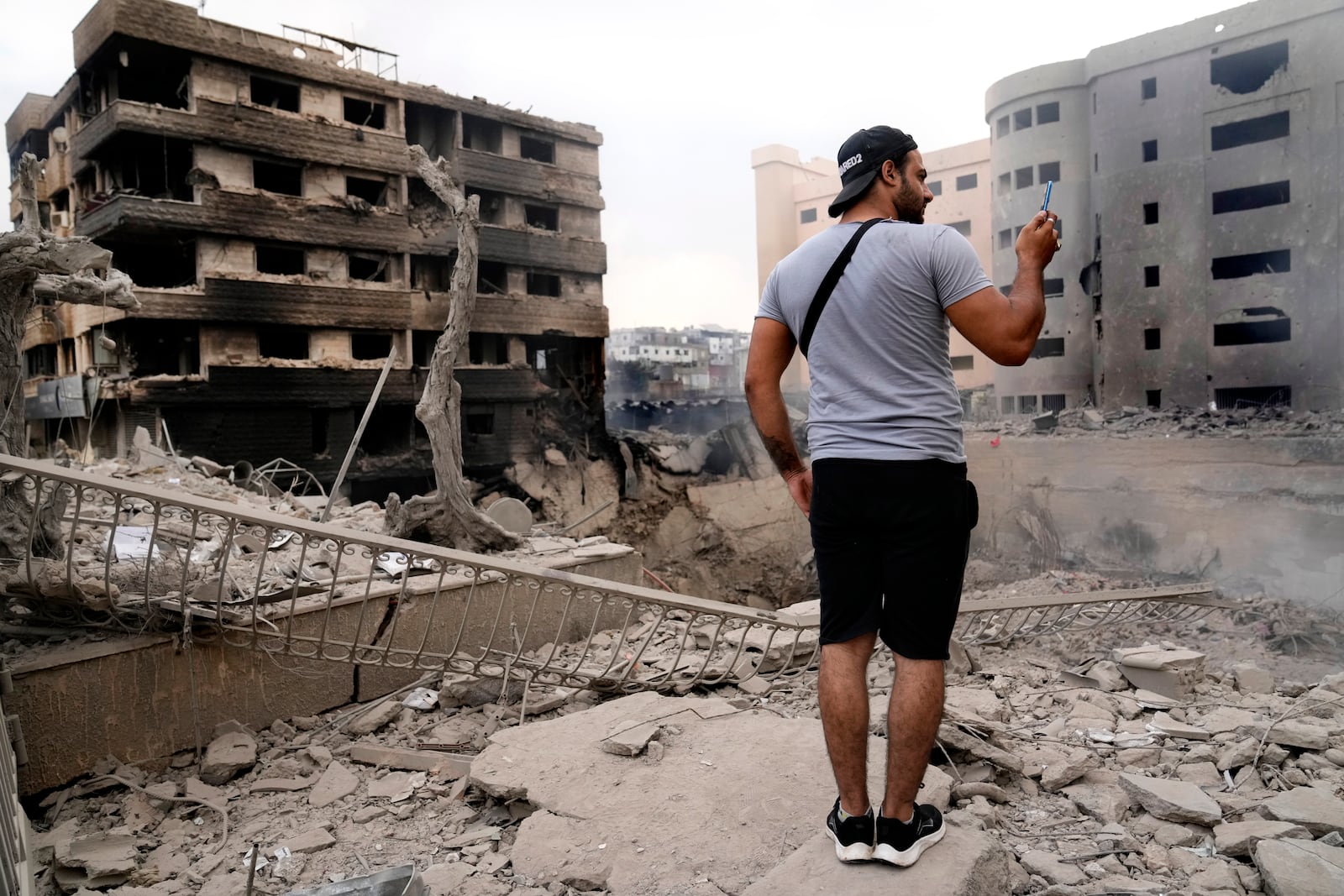 A man takes pictures by his mobile phone of destroyed buildings hit by Israeli airstrikes in Dahiyeh, Beirut, Lebanon, Monday, Oct. 7, 2024. (AP Photo/Hussein Malla)