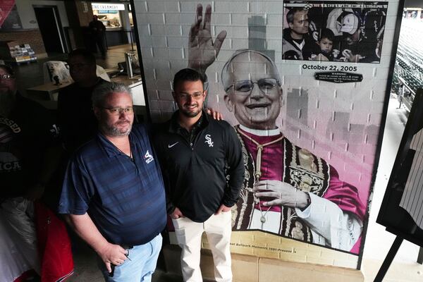 Eddie Schmit III, left, and his son Eddie Schmit IV, right, pose for a photo after a news conference for the Chicago White Sox's commemoration of team fan Pope Leo XIV with a graphic installation at Rate Field before a baseball game between the Seattle Mariners and the White Sox in Chicago, Monday, May 19, 2025. (AP Photo/Nam Y. Huh)