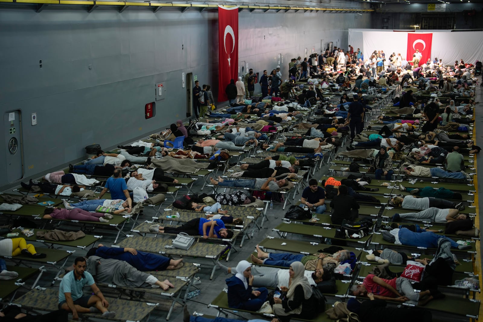 Hundreds of people, mostly Turkish citizens, rest on board of a Turkish military ship evacuating them from Lebanon to Turkey, in Beirut port, on Thursday, Oct. 10, 2024. (AP Photo/Emrah Gurel)